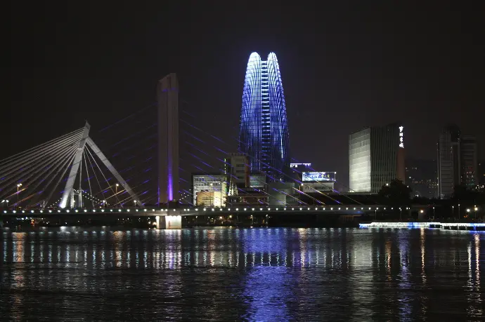 a city skyline at night with a bridge over water