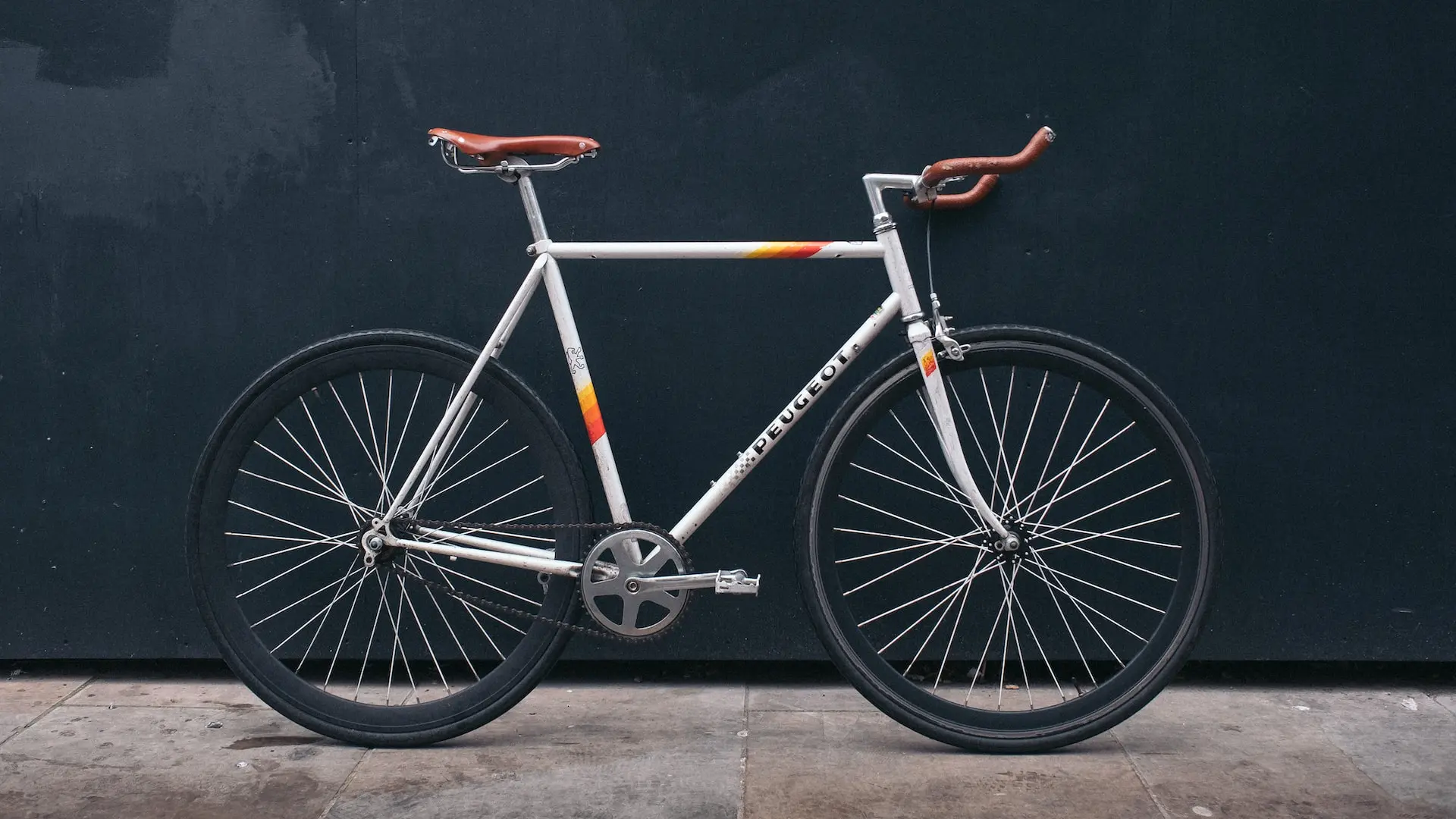 gray fixie bike leaning on black wall